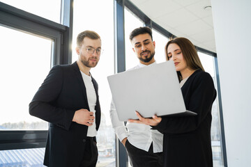 Three office workers watching a project on a laptop