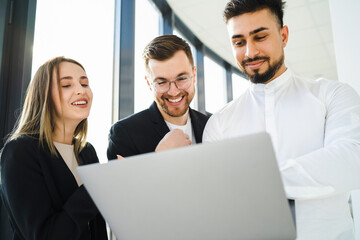 Joyful office workers looking at laptop