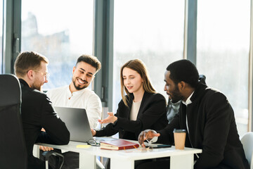 Group of young business partners have a meeting in the office sitting at a laptop