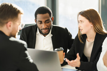 Woman boss with coffee cup showing her employees a business development model on a laptop