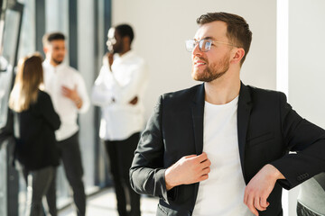 Confident male boss in the office against the background of his colleagues