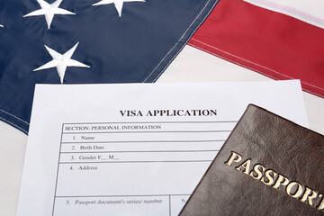 Visa application form and passport on American flag, closeup
