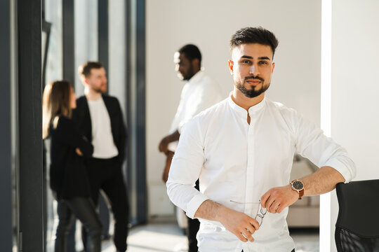 Portrait of a male boss in a white shirt and his employees in the background in the office