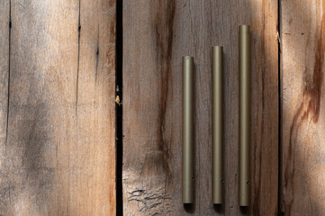 Three green aluminum tubes against a wooden background. Rough, cracked boards. Natural lighting. Close-up. Selective focus.