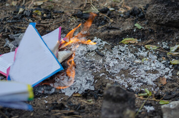Burning sheets of torn notebook. Multicolored sheets burn into gray ash.