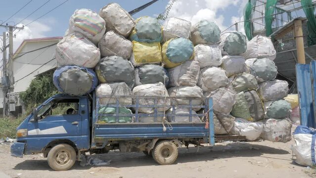 side view of a stationary small truck overloaded with sorted plastic bottles into big bags