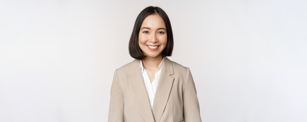 Portrait of successful businesswoman in suit, smiling and looking like professional at camera,...
