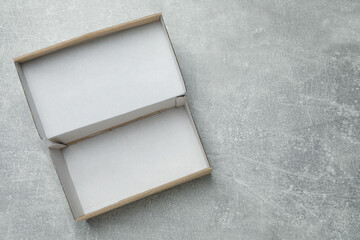 Empty open cardboard box on grey table, top view. Space for text