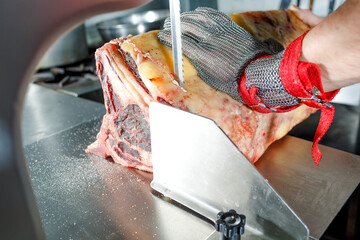 a chef in a metal glove cuts an wet-aged ahd Dry-Aged on an electric knife 