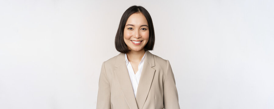 Portrait of successful businesswoman in suit, smiling and looking like professional at camera, white background