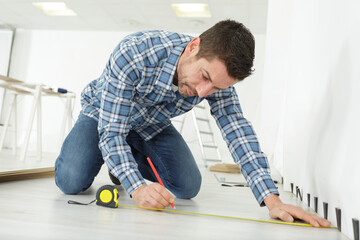 a man measuring wood floor