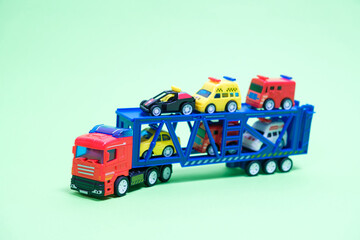 Red toy plastic car transporter with special equipment inside on a green background, toys for boys