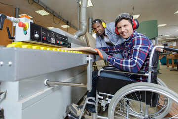 disabled worker in wheelchair and colleague in a factory