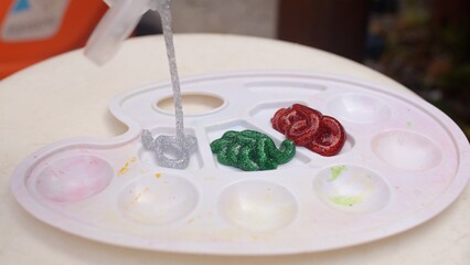 Acrylic with glitters is laid out on a palette from a tube. Close up. Beginning of the beginners painting course.