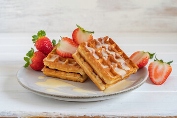  Waffles with fresh strawberries on gray plate over white background.