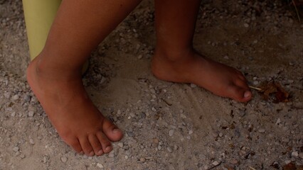 A close-up of naked feet of kid on the sand in the playground. Being barefoot boosts brain development in children.