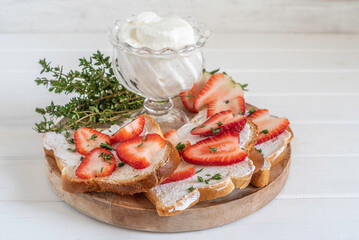 Sandwiches with cottage cheese and fresh strawberries over wooden background with copy space.