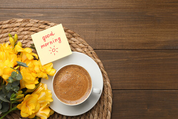 Cup of aromatic coffee, beautiful yellow freesias and Good Morning note on wooden table, flat lay. Space for text
