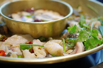 spicy sichuan hot pot with boiled fish, red chili pepper and coriander close up view
