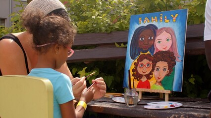 Mom teaches child to properly hold a brush in hands during joint art session. The coordinated...