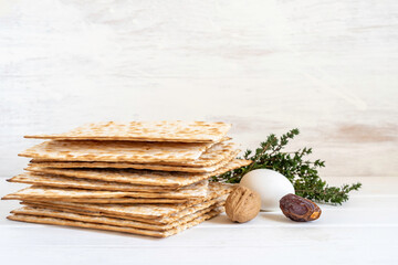 Matzah bread, walnuts, dates for Jewish holiday Pesach on white wooden background with copy space.