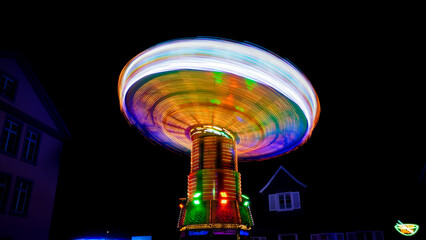 Colorfully illuminated chain carousel at a funfair in Germany at night with abstract motion blur...