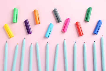 Many colorful markers on pink background, flat lay. School stationery