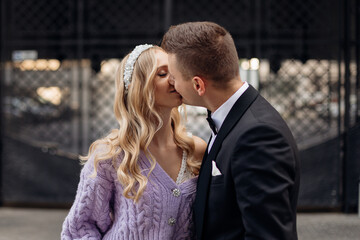 Beautiful couple of bride with long wavy fair hair in bridal dress, lilac cardigan with bandeau on head and bridegroom.
