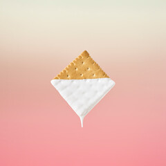 Creative food concept of biscuits dipped in white milk. A quick healthy and tasty snack on pastel pink background.