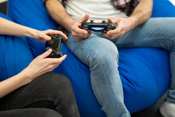 Close-up of the hands of a man and a woman enjoying playing video games  with a console gamepad in their hands.