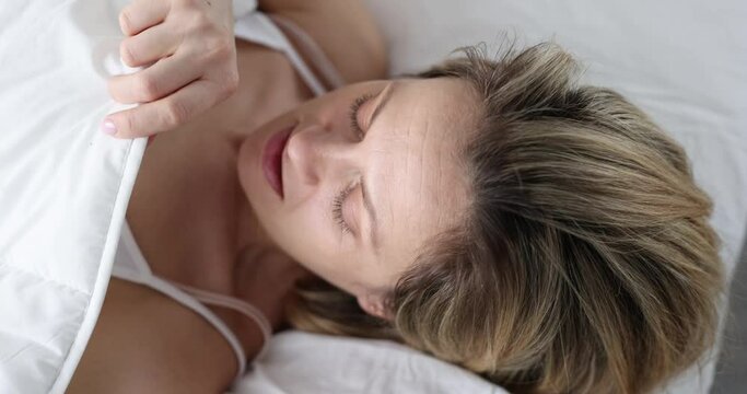Woman looks in shock under covers while lying in bed