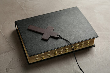 Wooden Christian cross and Bible on grey table