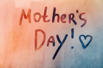 Text Mothers Day and heart shape written finger won orange sunset wet window