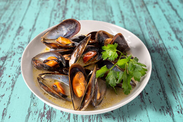 Mussels cooked with an Italian recipe called tarantina mussels in white, in a plate with parsley on...