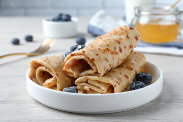 Delicious crepes with blueberries on white wooden table, closeup