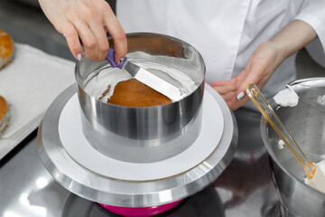 Pastry chef aligns the cream with a spatula