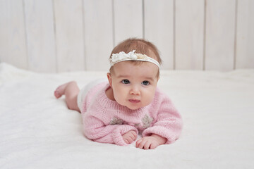 Cute baby girl in knitted clothes and wreath. Mother's day greeting card. International day of happiness