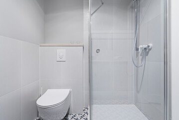 Nowoczesna jasna łazienka w kolorach białych i szarych. Toaleta, prysznic, blat z umywalka i...