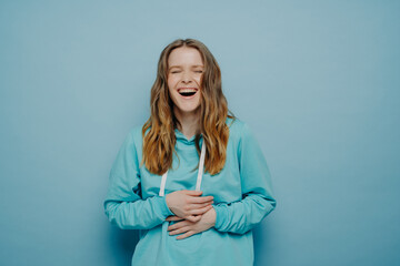 Laughing female with hands on belly posing in studio