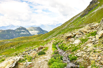 Fototapeta na wymiar Beautiful mountain landscape with rocky hiking path near Les Arcs 2000 ski station in Red Peaks massif in summer. Savoie, France. Scenic view. Alpine scenery background. Wanderlust, wandering concept.