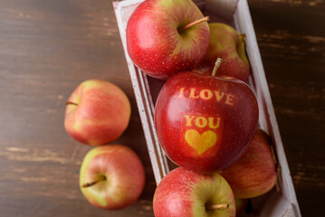 Red apple with text I Love You in wooden crate on table