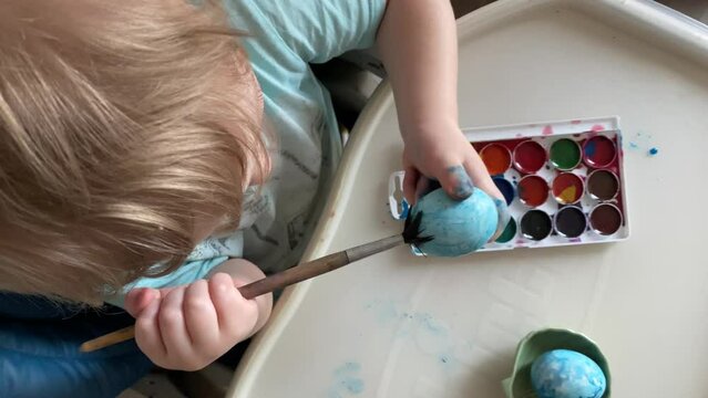 Little boy paints eggs for Easter with his mother