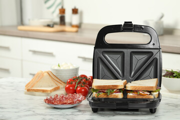 Modern grill maker with sandwiches and different products on white marble table in kitchen