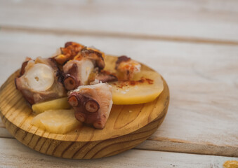 Spanish food tapas. Typical dish from the Spanish region of Galicia: octopus with paprika served on a wooden plate.