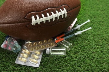 American football ball and different drugs on green grass, closeup. Doping concept