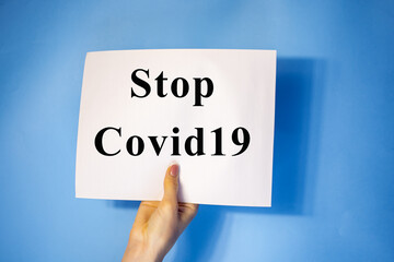 man hand holding blank card paper sheet isolated on blue background with copy space.Holding a sign that says Covid 19