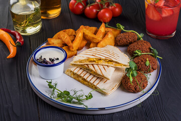 Grilled quesadillas with falafel on black wooden background