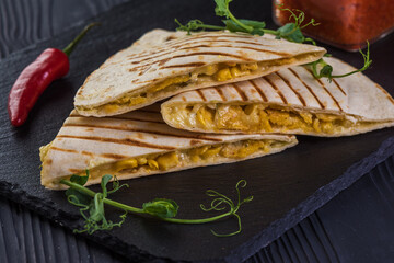 Grilled quesadillas on black wooden background