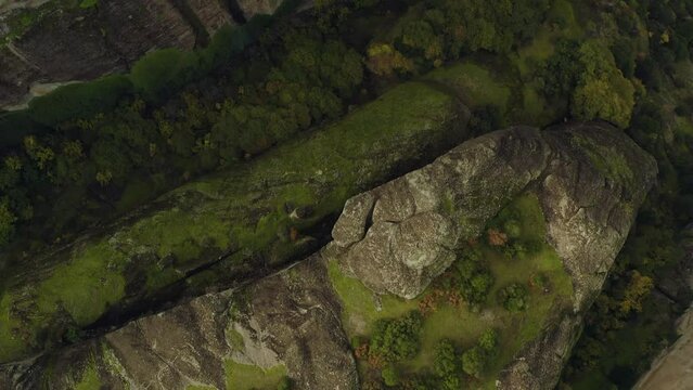 Aerial view above steep, sandstone pillars and clifftop buildings in Meteora, Greece - top down, drone shot