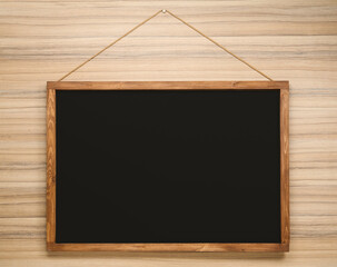 Clean black chalkboard hanging on wooden wall